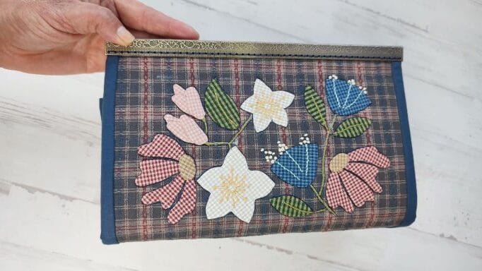 estuche con mariposa y flores aplicadas con tres bolsillos de cremallera y multibolsillos laterales, con cierre metalálico que se cose a mano.. Diseño de tomatwins