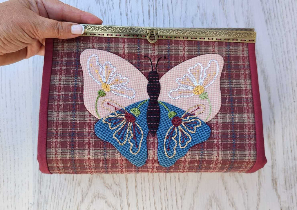 estuche con mariposa aplicada con boquilla metálica tipo cofre. Con tres bolsillos de cremallera y múltiples compartimentos.